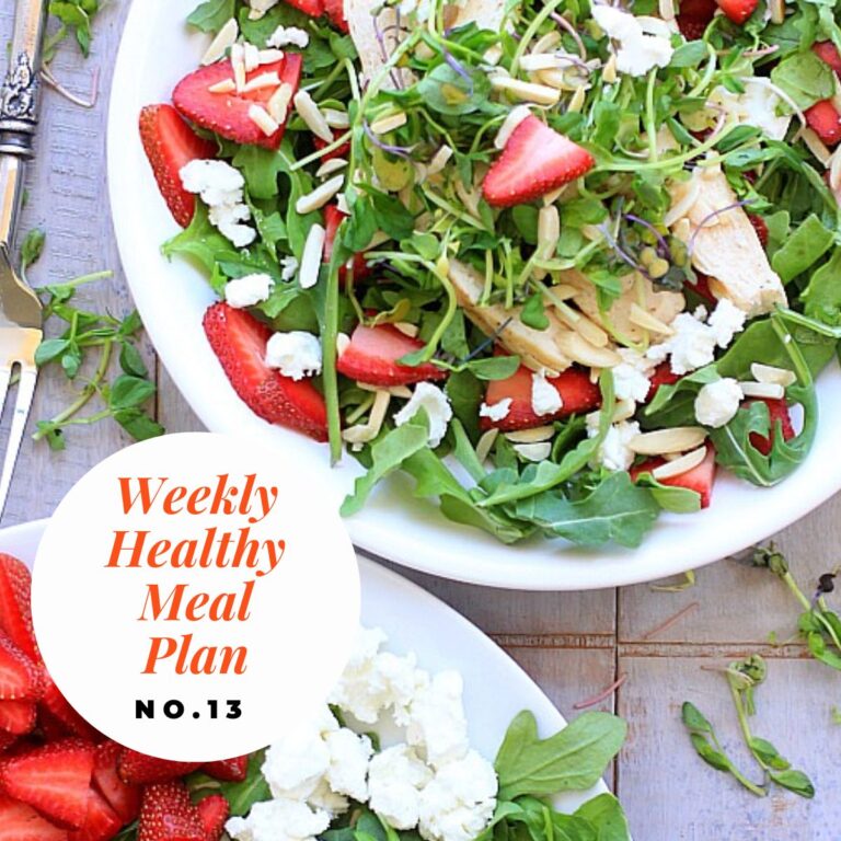 Two white plates topped with a strawberry arugula salad with chicken.