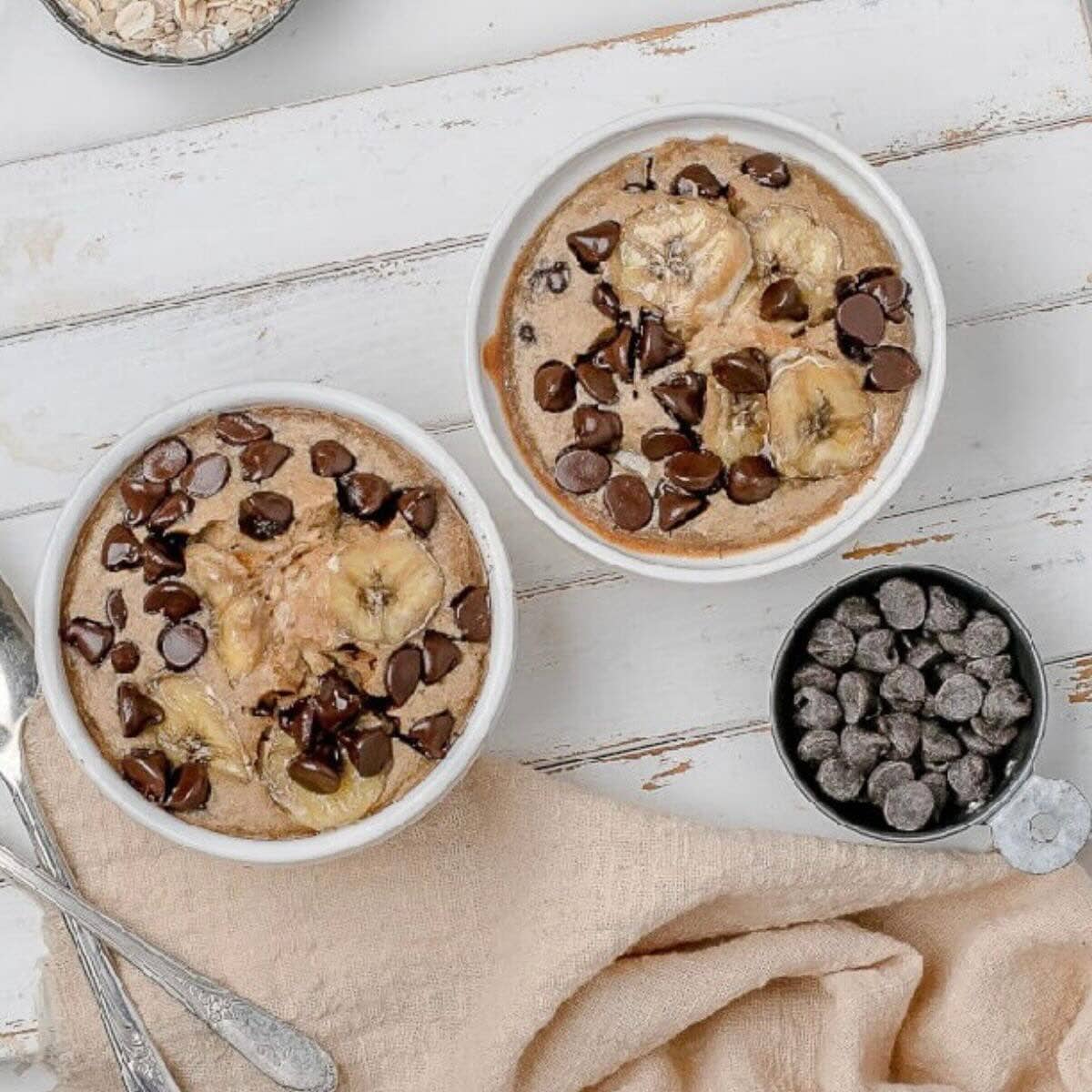 Two white ramekins with banana bread chocolate chip baked oats.