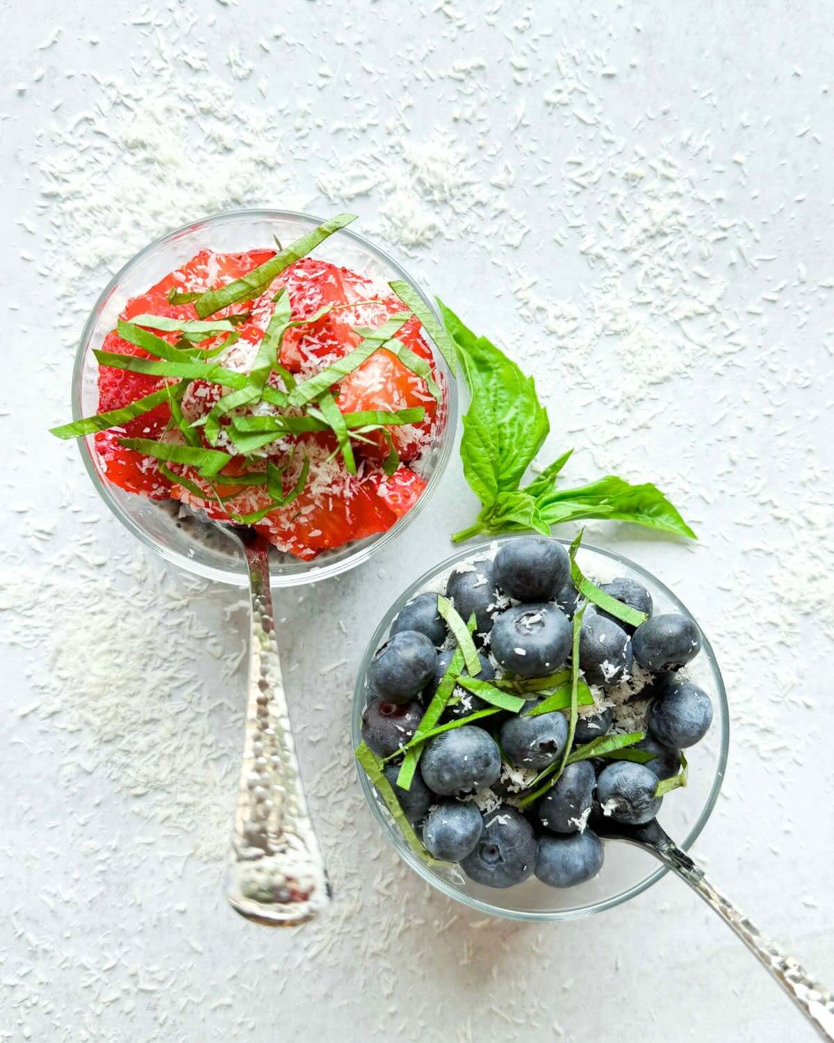 Overhead shot of basil seed pudding topped with strawberries and basil and blueberries and basil.