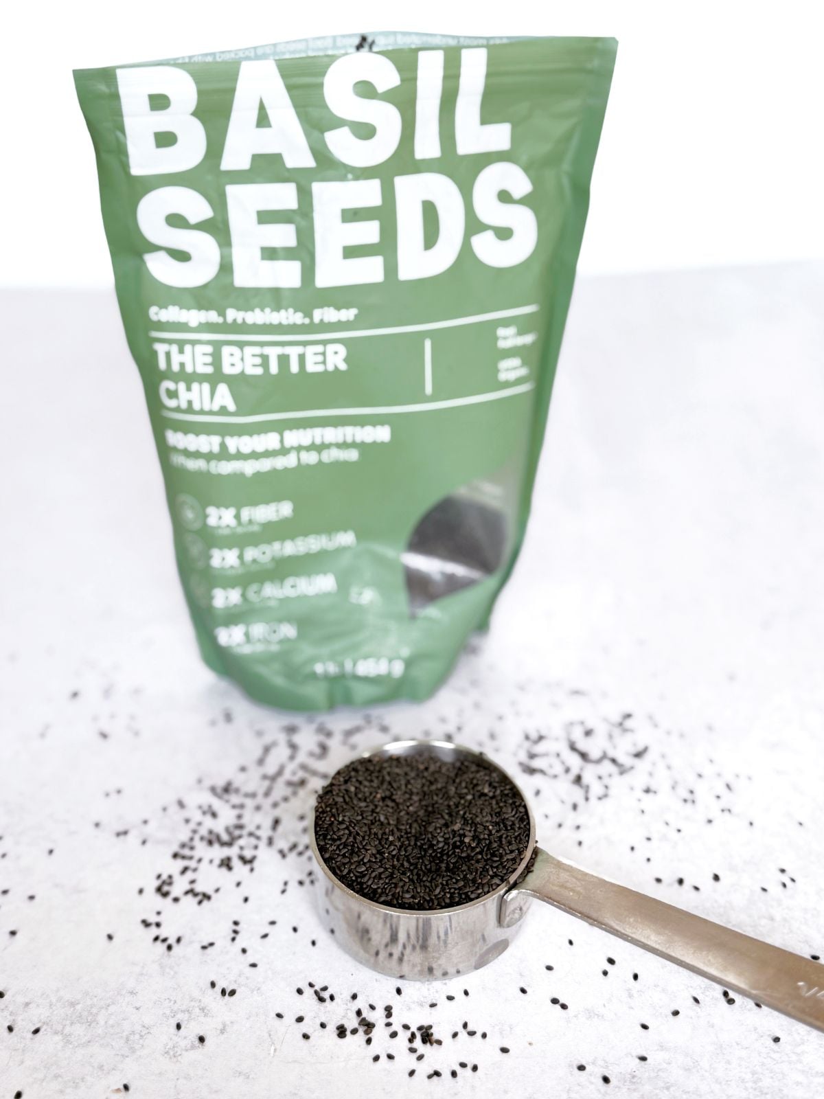 Measuring cup filled with basil seeds and a basil seed package in the background.