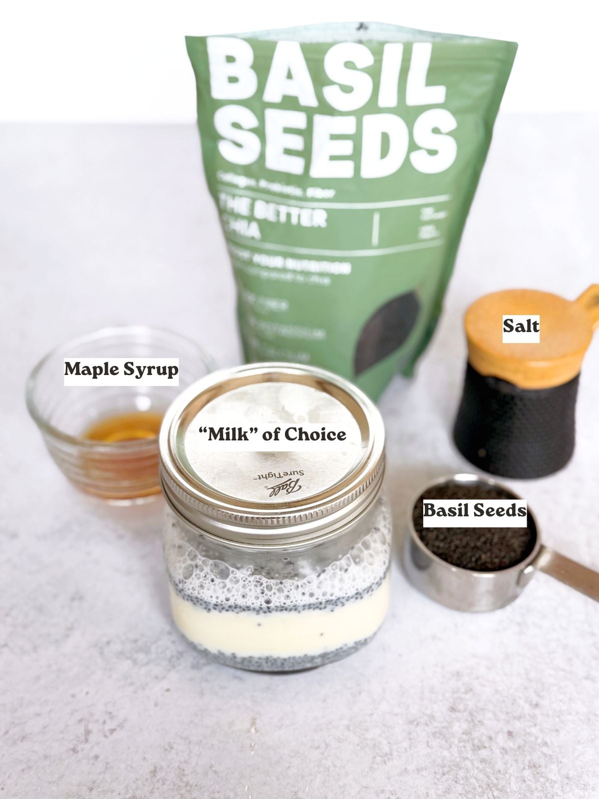 Ingredients to make basil seed pudding including milk, basil seeds, maple syrup, and salt.