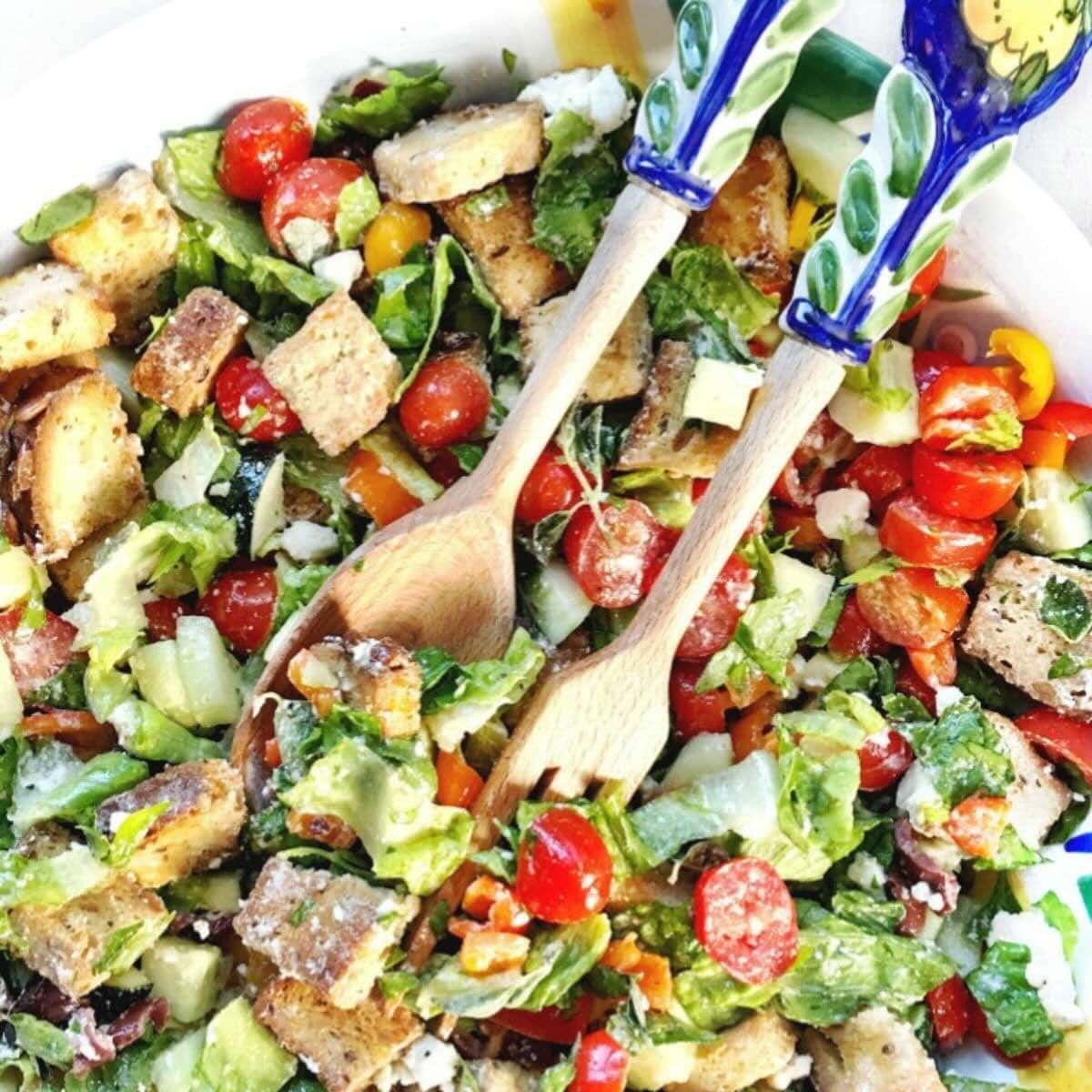 Panzanella salad with bread, tomatoes, fresh herbs, and other vegetables in a colorful bowl.