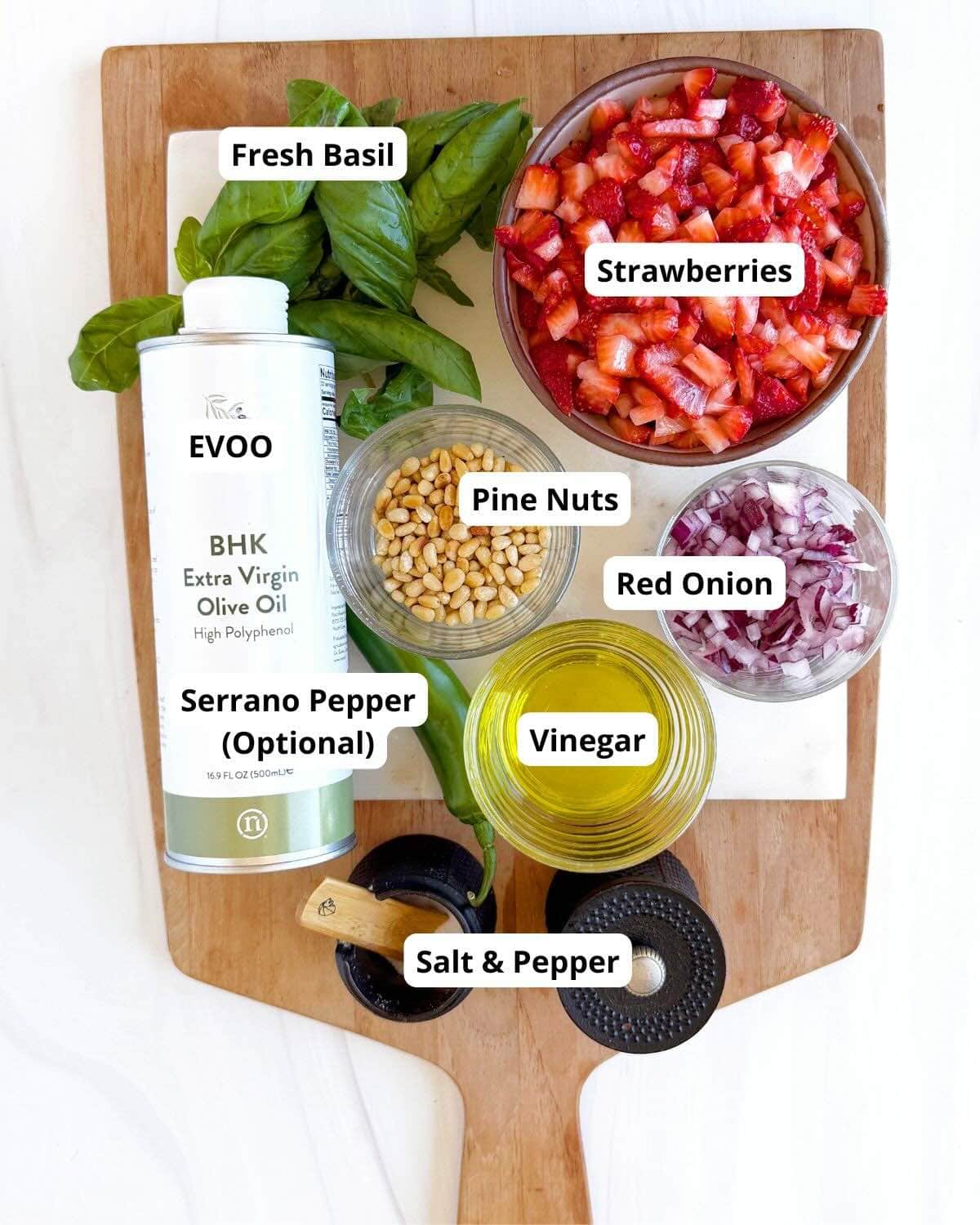 Tray with ingredients including strawberries, basil, red onion, pepper, pine nuts, extra virgin olive oil, vinegar, salt, and pepper.
