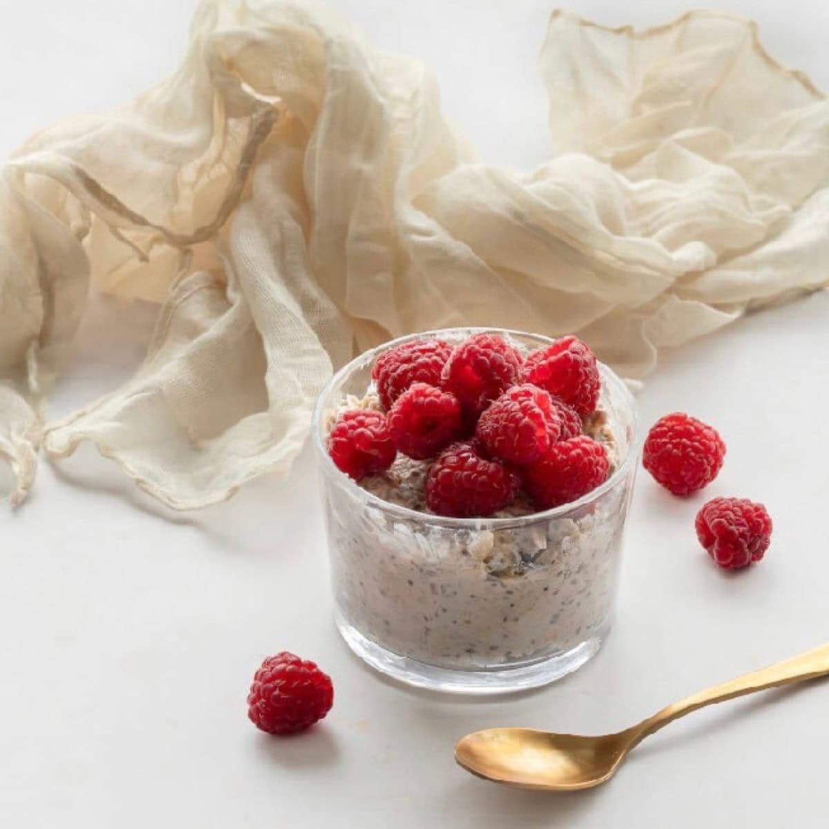 Overnight oats in a glass topped with raspberries.